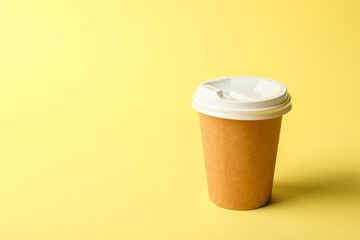 One paper cup on yellow background. Mockup for design