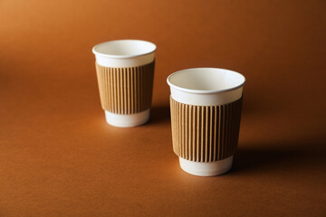 Paper cups on brown background, selective focus. Mockup for design