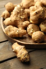 Raw Jerusalem artichokes on wooden table, closeup