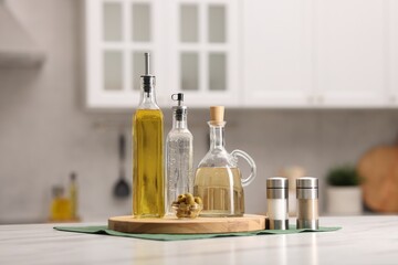 Bottles of salad dressings, salt, pepper and olives on white table in kitchen