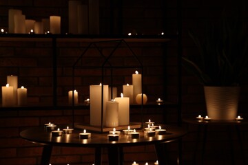 Many burning paraffin candles in dark room