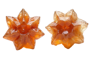 Two glistening star shaped candies radiating warmth on a pure black background with sharp focused light