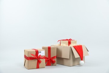 Parcel with gift boxes and Santa hat on light background