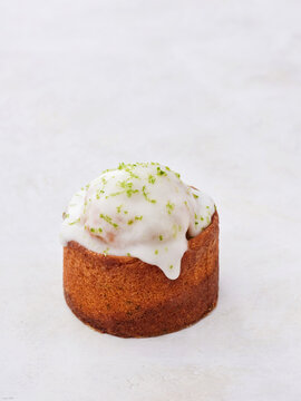 A delightful cake sits invitingly on a light surface, embellished with smooth frosting and a hint of lime zest on top, enticing taste buds with its sweetness