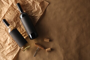 Bottles of wine, corkscrew and corks on parchment paper, flat lay. Space for text