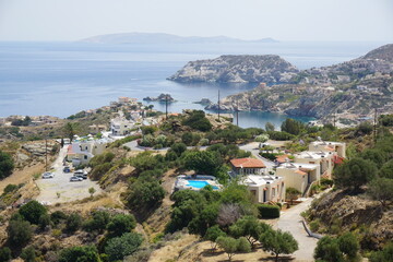 Obraz premium Panoramic view of Agia Pelagia in Crete, Greece from above with the blue sea and the clear blue sky in the background - Holiday homes, villas and hotels with swimming pools amidst beautiful vegetation