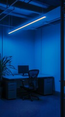 Blue-lit modern office workspace at night, featuring a desk, chair, computer, and plant. Ideal for themes of work, technology, and tranquility.