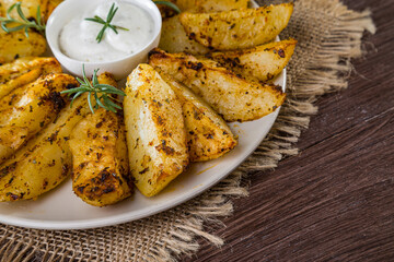 Baked new potatoes with spices and creamy sauce in a plate on a wooden table