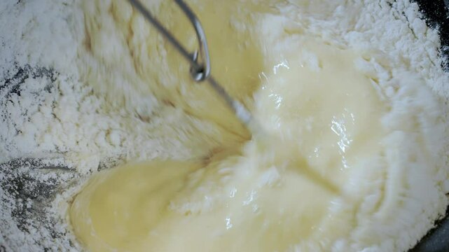 Food preparation. Top dow view, close-up of thin pancake, making crepe batter. Stir the batter liquid in a dark bowl. Slow motion footage 100fps.