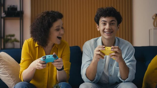 Excited mom and her teen son enjoying a video game, boy celebrating victory