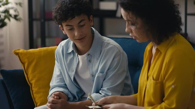 Mother giving pocket money to her pleased teen son, offering financial support
