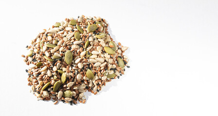 A mix of different seeds on a white background. Sunflower seeds, black and white sesame seeds, flax and pumpkin seeds - all together. Healthy food.