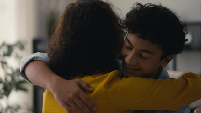 Smiling teenage son presenting a flower bouquet to his mom, birthday celebration
