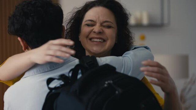 Cheerful middle-aged woman embracing her teen son visiting family, warm reunion