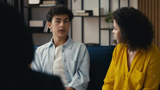 Annoyed mom arguing with her rebellious son during a session with a counselor