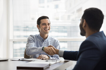 Happy Hispanic businessman shaking hands Indian male partner start teamwork or negotiations in...