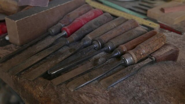 A variety of Woodworking Chisels delicately placed on a well-organized Workbench surface