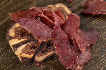 dried dried meat from meat tenderloin with spices and salt on black slate