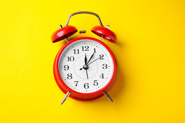 Red alarm clock on yellow background, top view