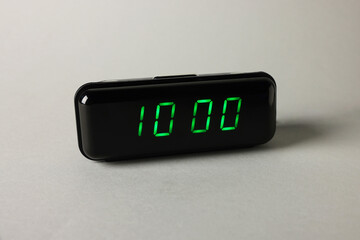 Digital alarm clock showing 10:00 o'clock on grey background