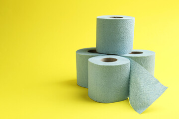 Light blue toilet paper rolls on yellow background, space for text