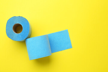Light blue toilet paper roll on yellow background, top view