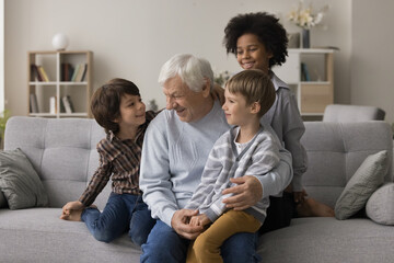 Visiting grandpa. Loving senior grandfather meet little multiethnic grandsons gather grandkids...