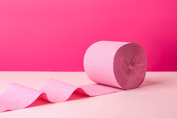 Color toilet paper roll on pink background. Space for text
