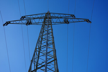 Blick nach oben auf einem Strommast mit blauen Himmel 