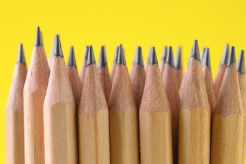 Many graphite pencils on yellow background, closeup