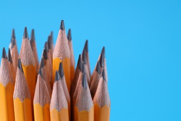 Many pencils on light blue background, closeup. Space for text