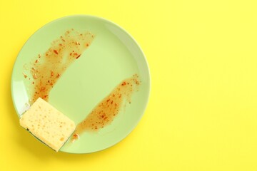 Dirty plate and sponge on yellow background, top view