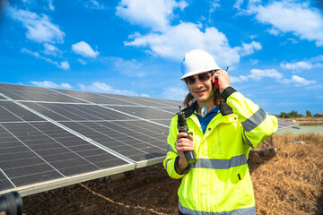 A technician wearing a high visibility jacket and helmet inspects the surface of a large solar...