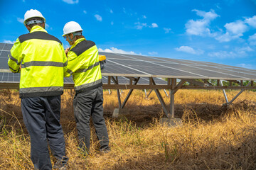 Team engineers in a high visibility jacket performs an inspection on the underside of a solar panel...