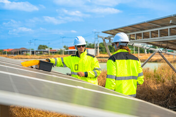 Team engineers in a high visibility jacket performs an inspection on the underside of a solar panel...