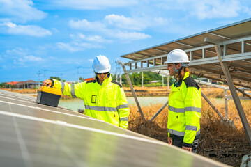 Team engineers in a high visibility jacket performs an inspection on the underside of a solar panel...
