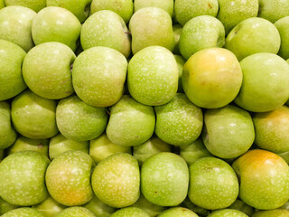 Beautiful and shiny green apples overlapping and arranged in the market