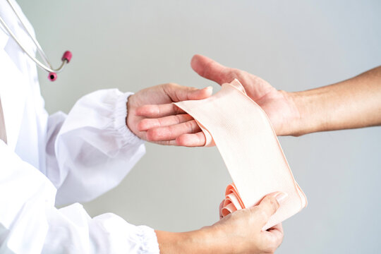 female doctor wrapping patient broken hand. customer in pain from injured wrist get help by emergency doctor to applying medical bandage to prevent hurt. wound patient hurt hand ankle need wrapping