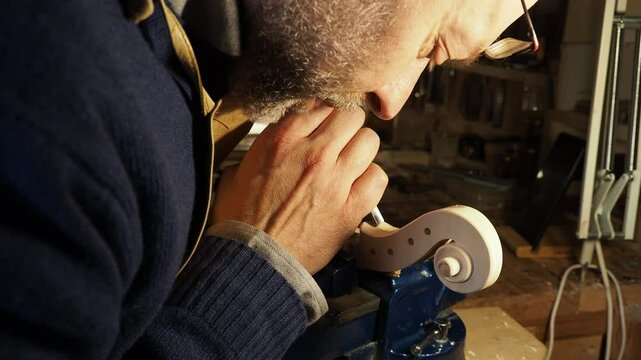 Expert violin maker handcrafting a wooden scroll, capturing the essence of meticulous instrument-making