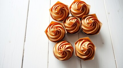 Fototapeta premium Orange cupcakes arranged on white wood. Image for baking blog or recipe