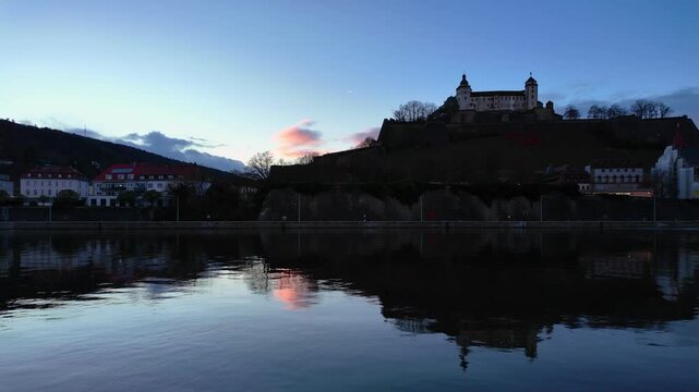 Amazing view of the Fortress Marienberg in W&uuml;rzburg, Germany. Bavarian castle with blue sky and sunset lights in blue hour. Beautiful reflections on the calm River Main in the foreground.