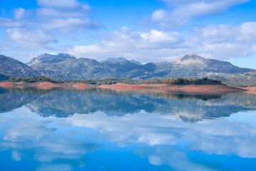 Beautiful landscape of lake and reflection of blue sky, clouds and mountains on surface of lake, Panoramic view of lake and snow-covered mountain and Forest trees calm in Jijel Algeria North African.