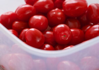 Close-up shot of a ripe red cherry tomatoes in a plastic container.
