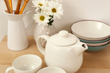 Composition with beautiful tea set, flowers and different kitchen stuff on wooden table