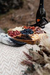 Close-up of a wooden snack tray with blueberries, cheese, sausages. Viking horns and champagne next to the tray.
