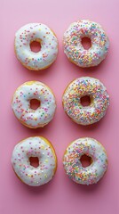 Colorful Donuts With Sprinkles Arranged in Two Rows on a Pink Background