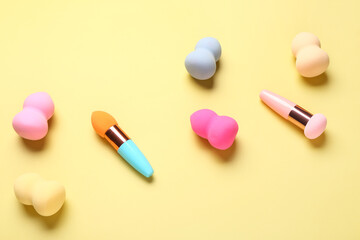 Different makeup sponges on yellow background