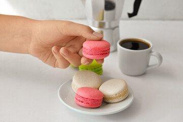 Woman holding sweet macaroons on white background