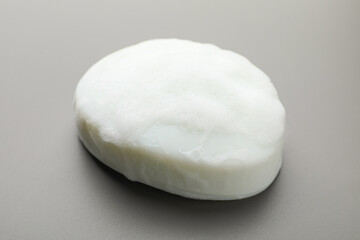 Soap bar with foam on grey background, closeup