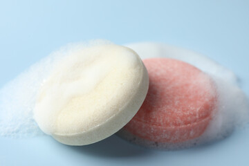 Soap bars with foam on light blue background, closeup